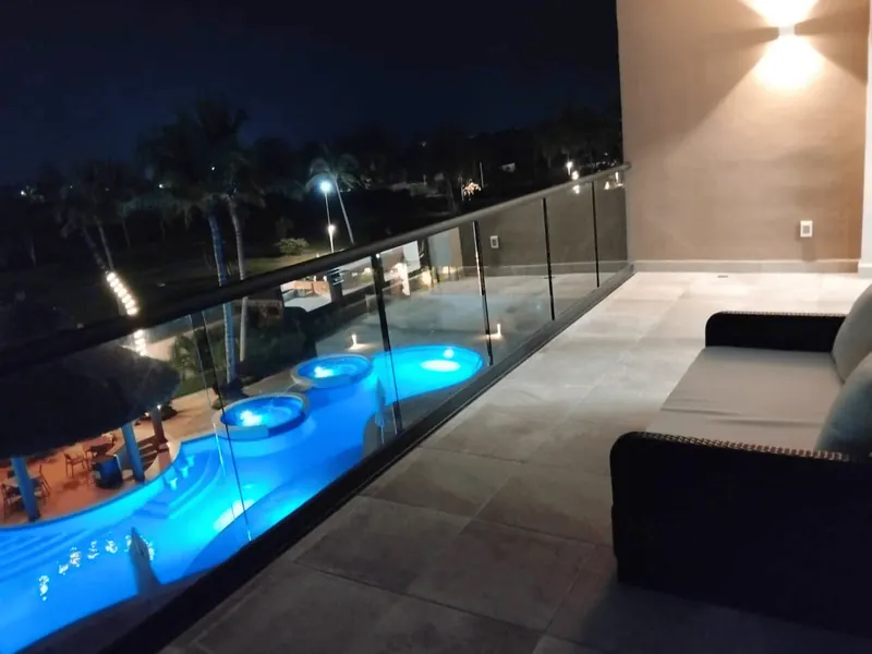 Terraza privada de noche, con vista a la alberca iluminada